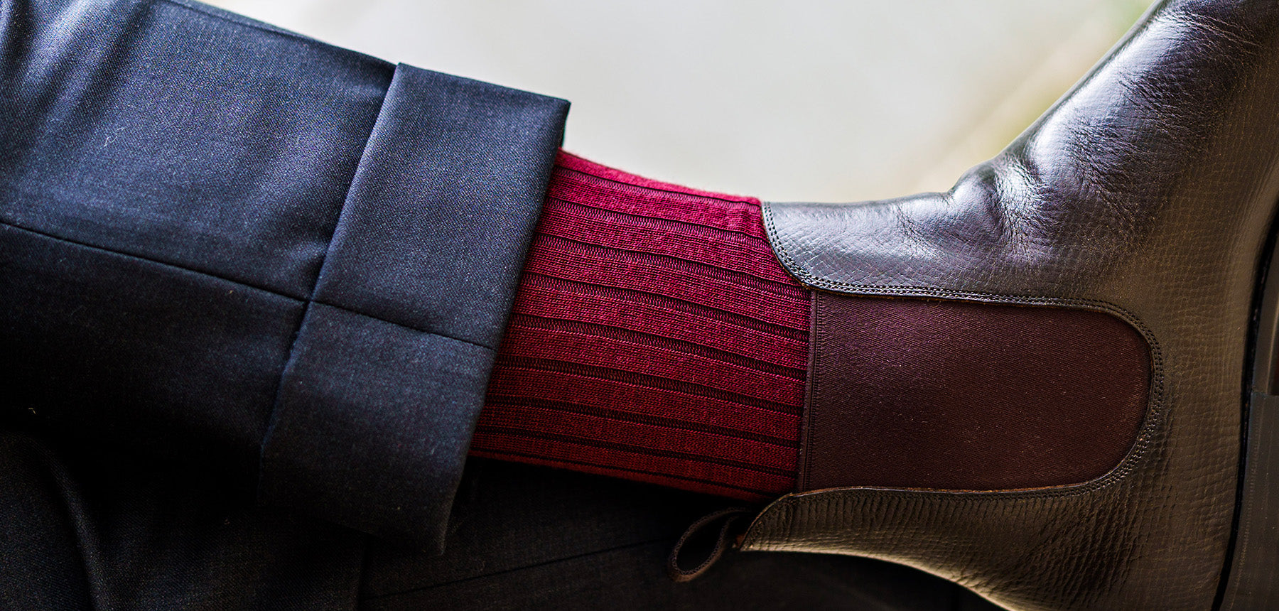 man wearing burgundy dress socks with chelsea boots and a grey suit