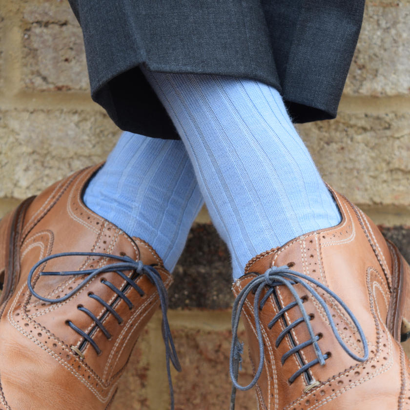 man crossing ankles wearing light blue dress socks