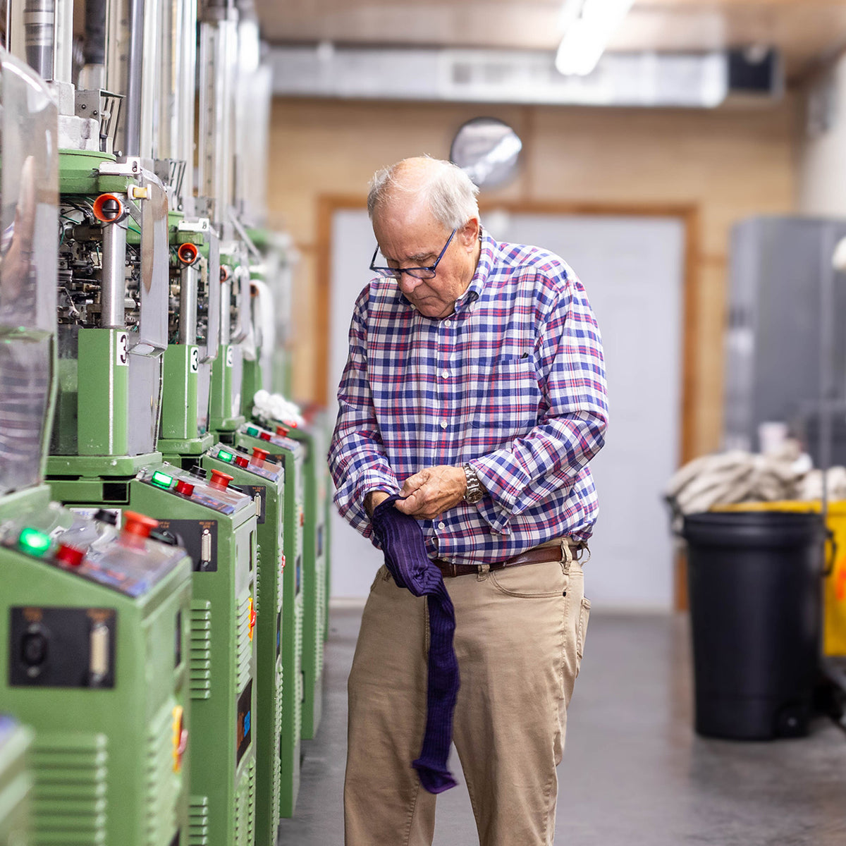 Mike James of Boardroom Socks standing beside knitting machines in hosiery mill