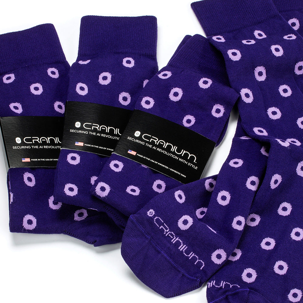 Four pairs of purple dress socks adorned with Cranium.ai logo and stylized CRANIUM stitched across the toe. Several pairs are wrapped with black, branded packaging.