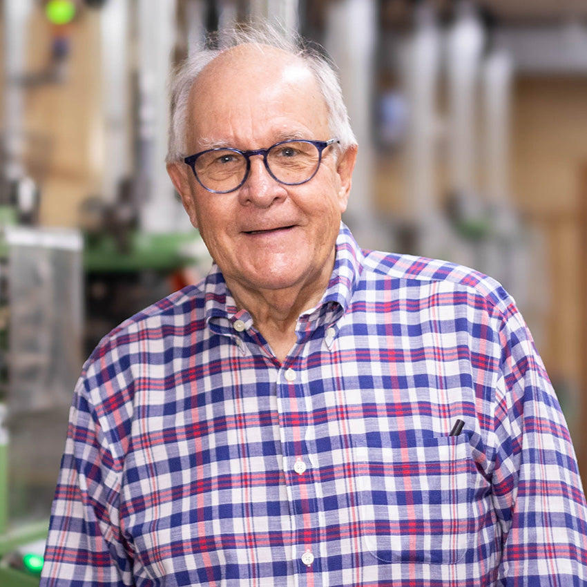 Headshot of Mike James, co-founder of Boardroom Socks, standing in front of knitting machines.