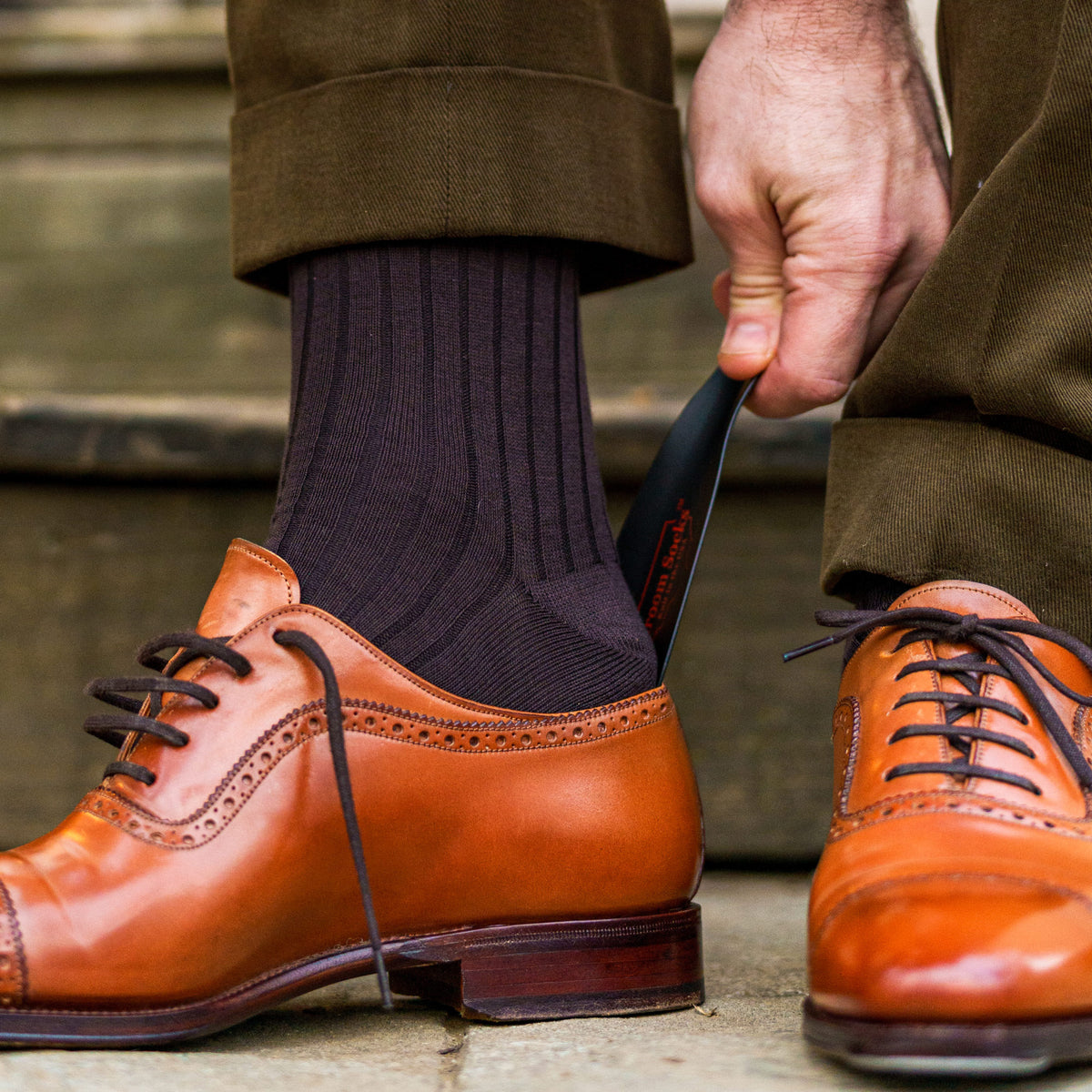 man putting on his shoe with a shoe horn wearing Brown Cotton Over the Calf Dress Socks