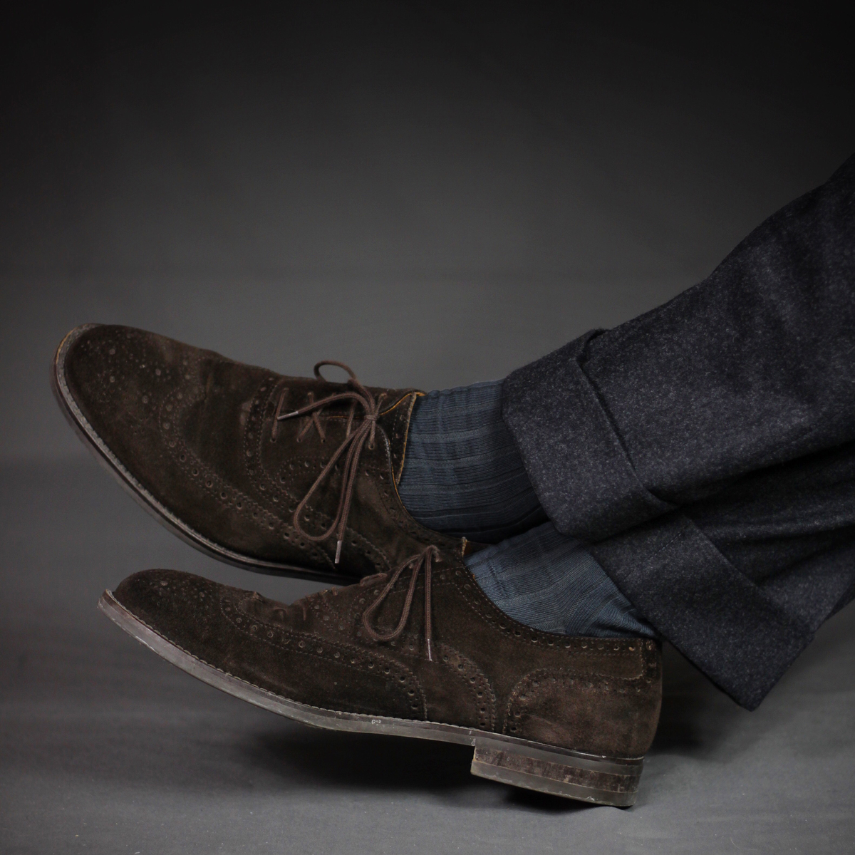 person sitting down crossing his legs wearingGrey Cotton Mid Calf Dress Socks on a grey background