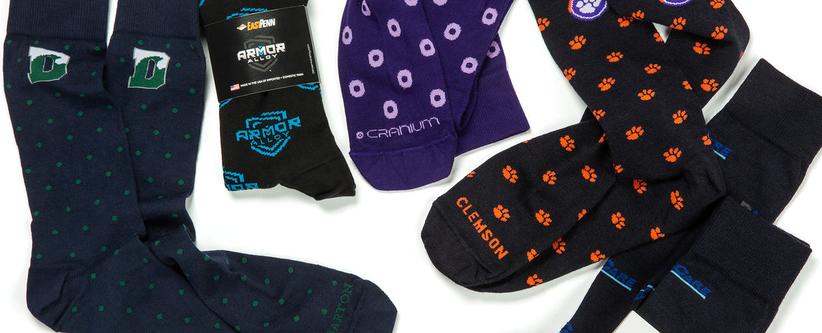 five different custom dress socks with various designs and colors on a white background