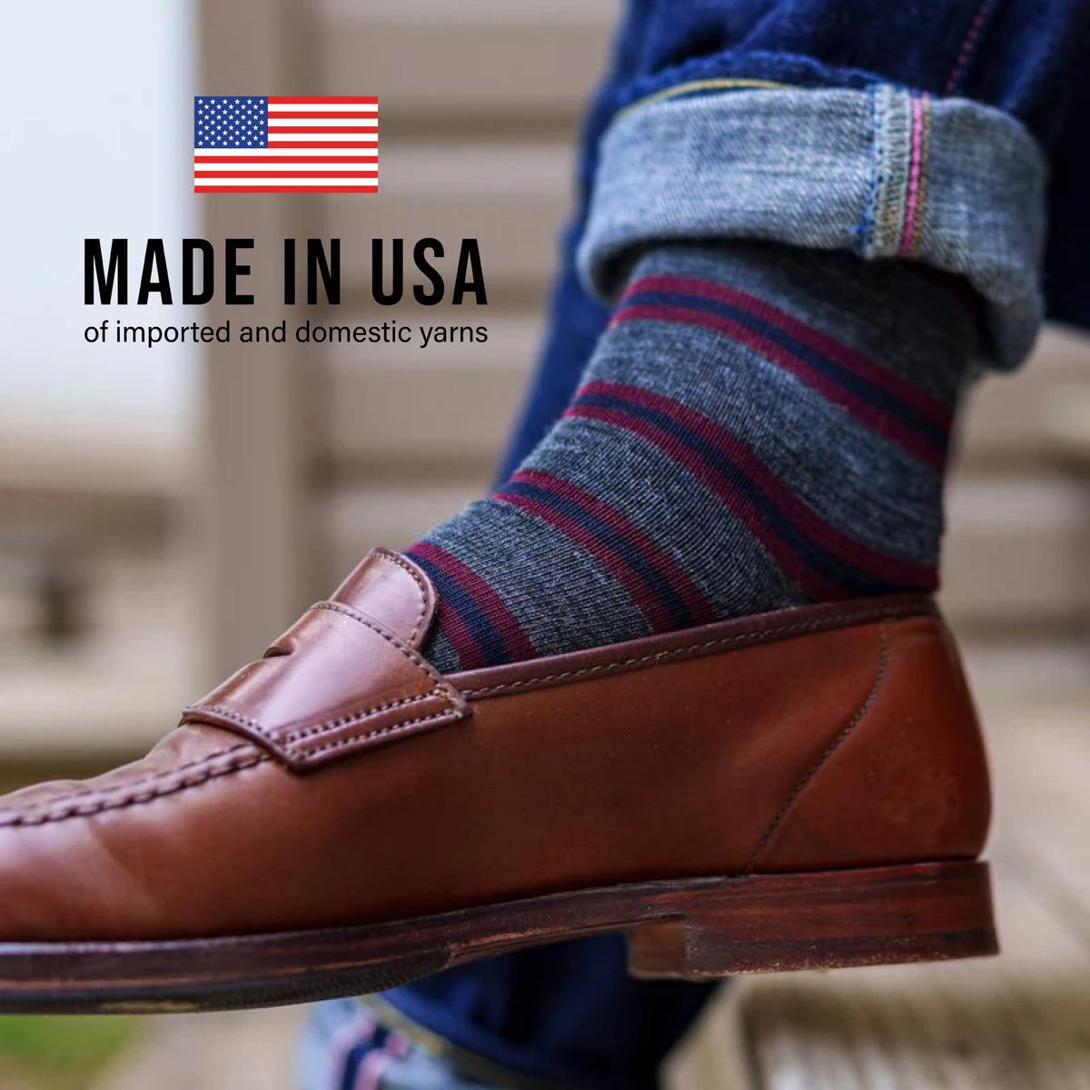 close up image of a man sitting down crossing his legs wearing jeans and Burgundy and Navy Stripes on Grey Merino Wool Over the Calf Dress Socks