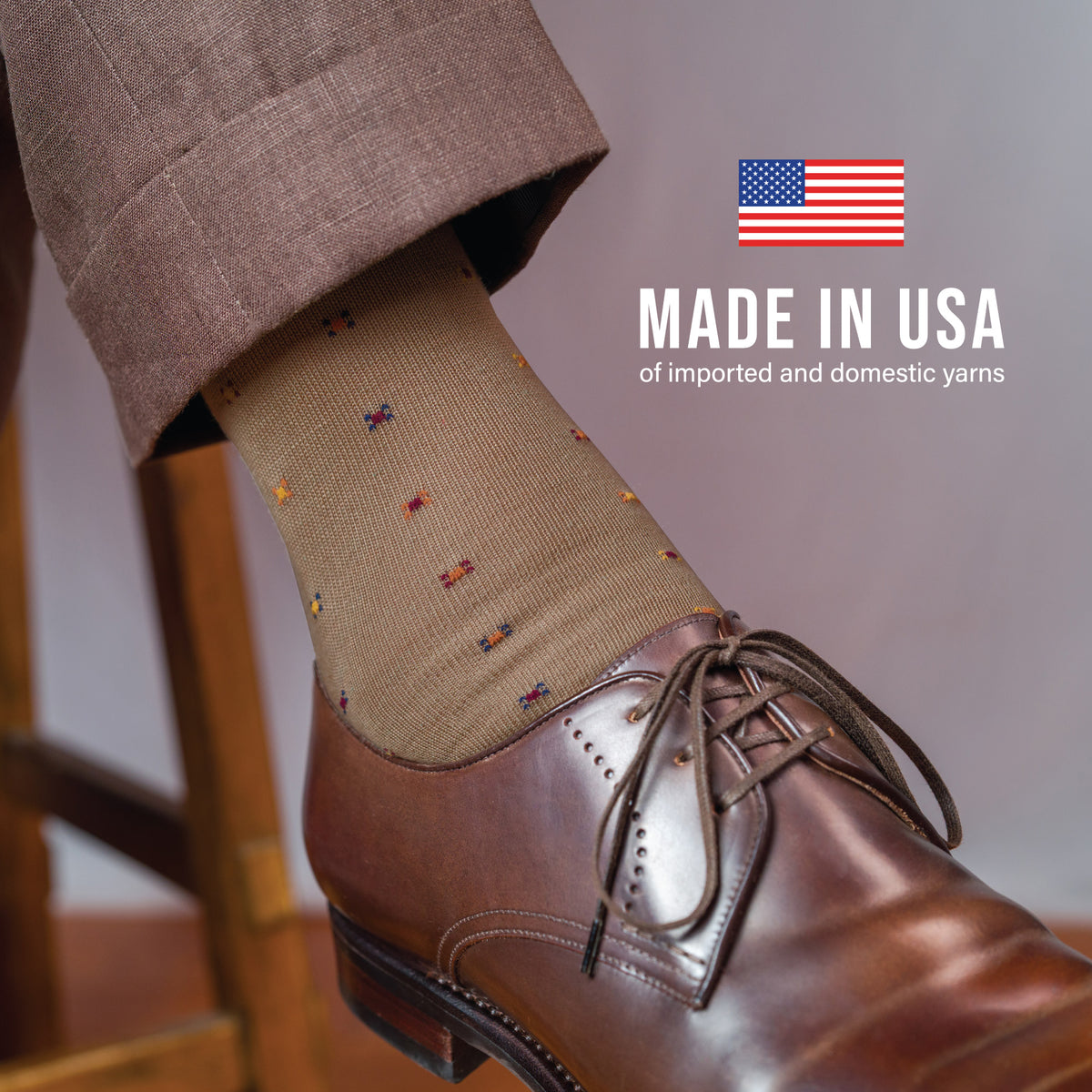 close up on a man sitting on a stool wearing khaki pants and Khaki Geometric Merino Wool Mid-Calf Dress Socks