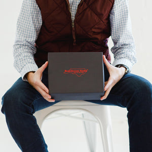 man seated holding closed Boardroom Socks gift box