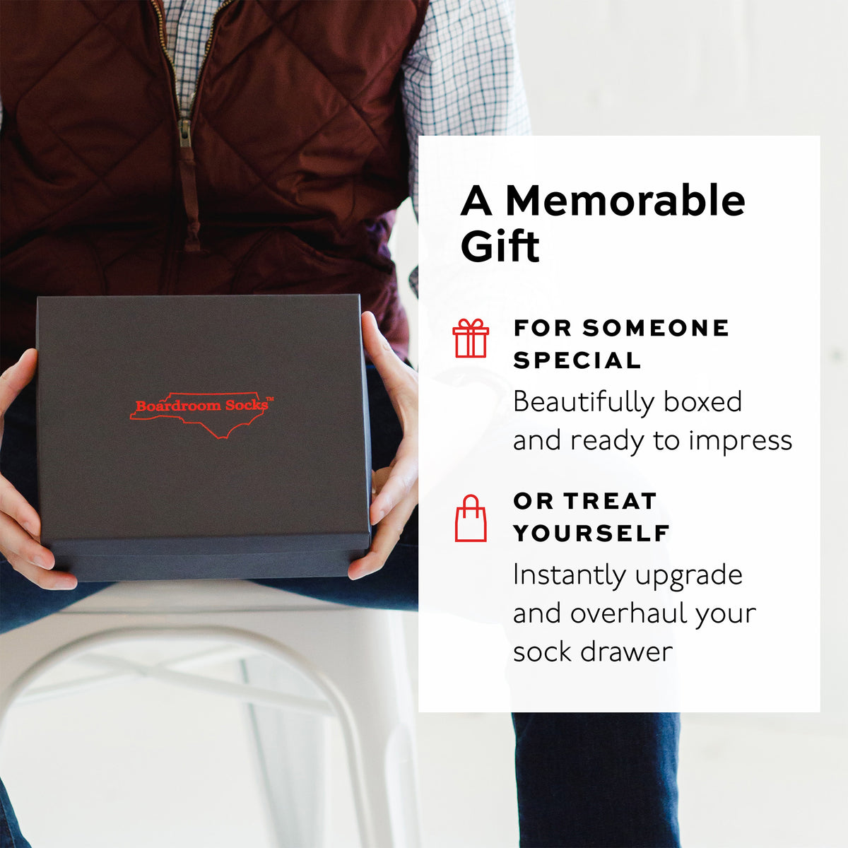 Person holding a black box with 'Boardroom Socks' branding, promotional text overlay.