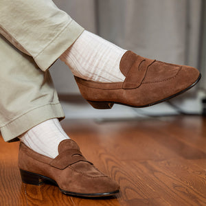man crossing legs wearing natural merino wool dress socks with light brown suede loafers and khakis