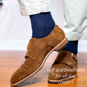 navy wool dress socks with tan chinos and brown suede monkstraps worn by man standing on hardwood floor
