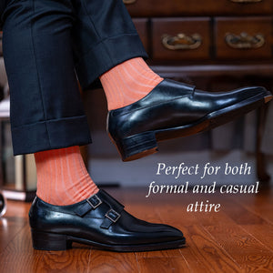 man crossing legs wearing peach dress socks with a dark suit and black monkstrap shoes