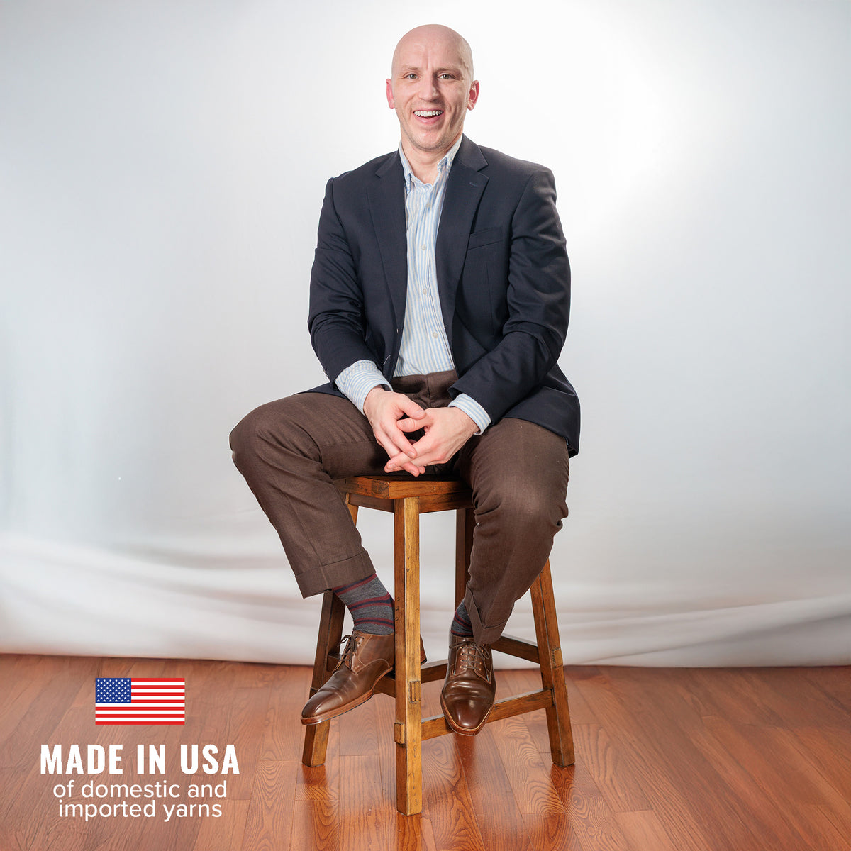 man wearing Boardroom Socks with business casual attire sitting on stool