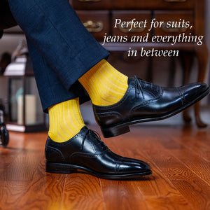 man crossing legs wearing yellow cotton dress socks with navy suit and black oxfords