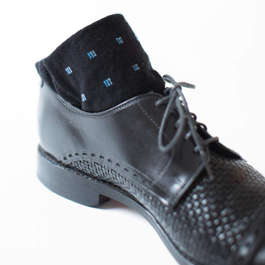 Pair of Black Wool Patterned Dress Socks Rolled up in Black Dress Shoes