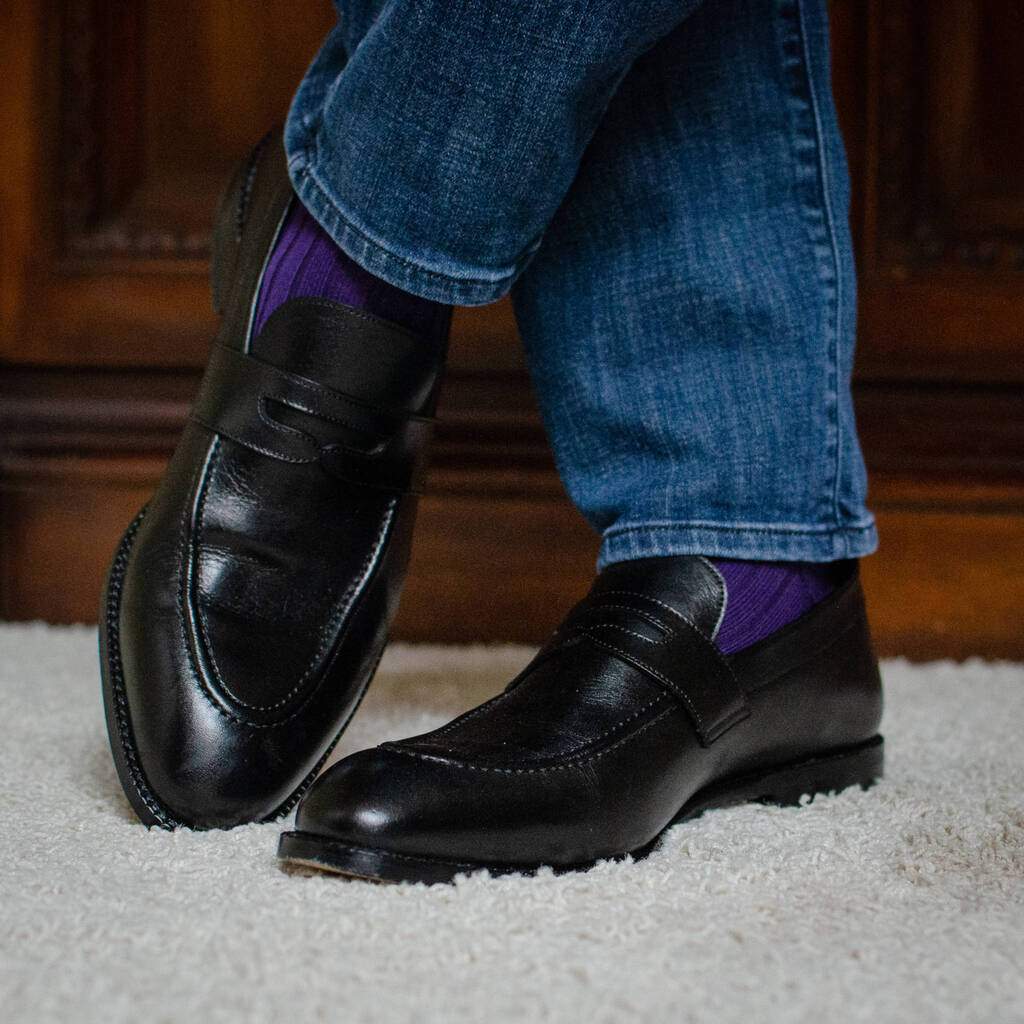 Man Standing On Plush Carpet Wearing Purple Dress Socks with Denim and Black Penny Loafers