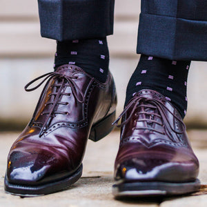 man taking a step wearing black and purple patterned dress socks for men