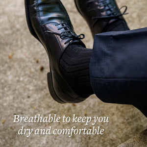 black dress socks with black dress shoes and navy pants on man crossing ankles