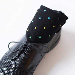 pair of patterned black dress socks rolled up inside a black dress shoe