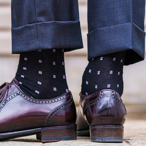 man standing showing black and purple patterned dress socks