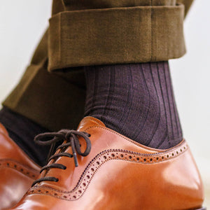 man crossing ankles wearing brown ribbed cotton over the calf dress socks