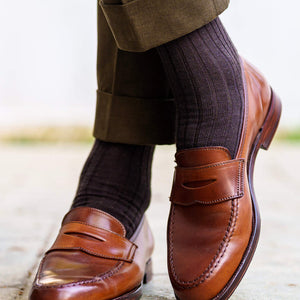 man wearing brown wool ribbed dress socks crossing ankles with light brown loafers and olive pants