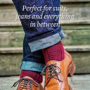 man wearing burgundy merino wool dress socks jeans and dress shoes while crossing ankles