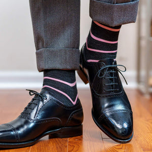 man walking wearing dark grey and light pink horizontal striped dress socks paired with light grey trousers and black oxfords
