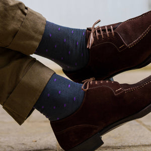man crossing ankles wearing purple polka dot grey dress socks with brown suede dress shoes