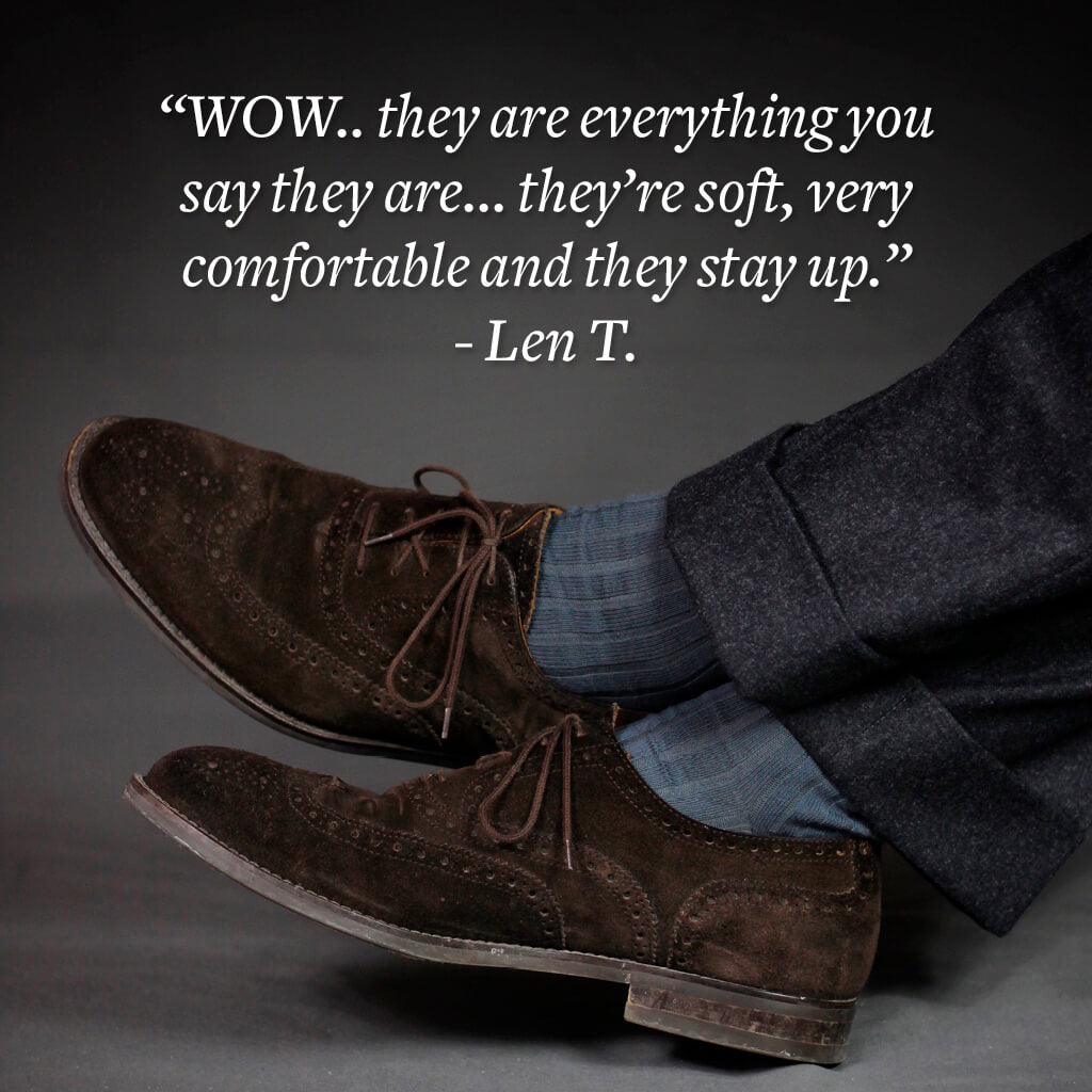 man crossing ankles wearing grey cotton dress socks and dark grey pants with brown suede brogues