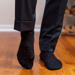 man taking a step in black dress socks decorated with bright red polka dots