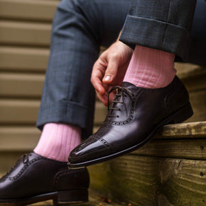 men's pink dress socks paired with grey trousers and beautifully shined brown oxfords