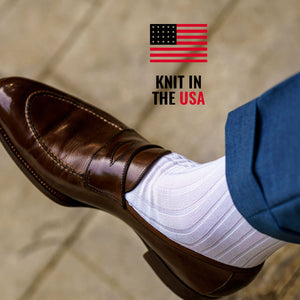 close up of white ribbed dress socks with dark brown penny loafers and light blue trousers