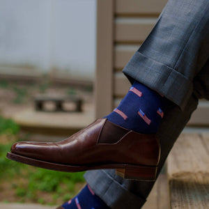 man crossing legs wearing navy dress socks with small American flags and grey dress pants