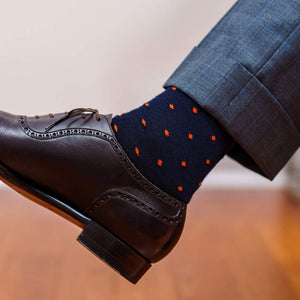 navy blue and bright orange patterned dress socks paired with dark brown oxfords and light grey windowpane trousers
