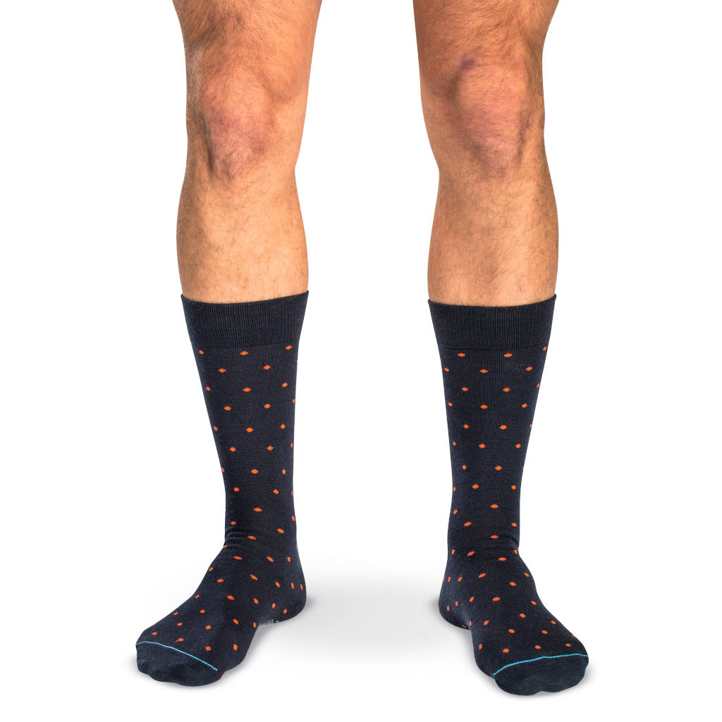 model wearing mid-calf length navy dress socks with orange polka dots