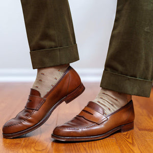 man wearing tan patterned dress socks with olive slacks and brown penny loafers walking on hardwood floor