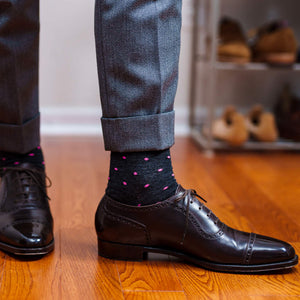 dark grey dress socks decorated with bright pink dots paired with grey trousers and dark brown oxfords