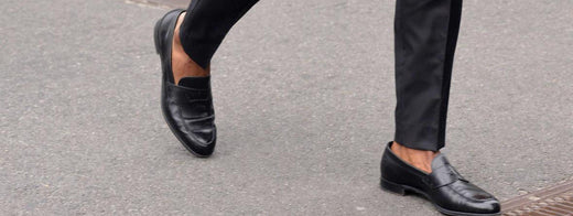 man walking wearing black dress shoes with no socks