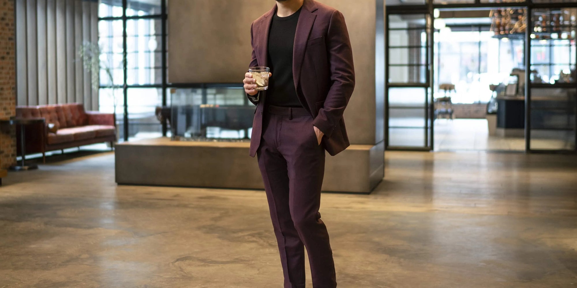 man holding cocktail wearing burgundy suit with black t-shirt