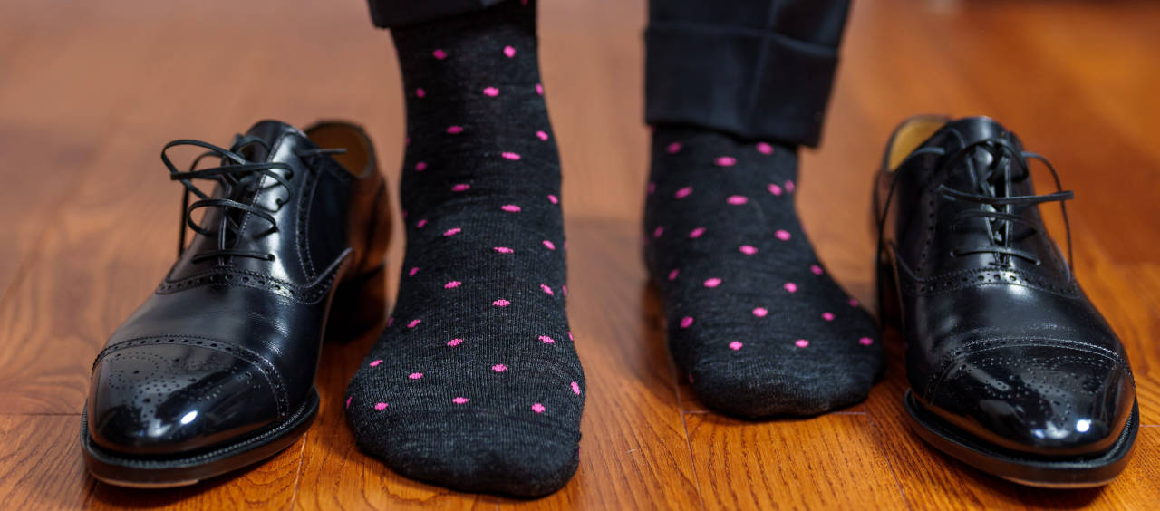 man wearing designer dress socks standing on beautiful hardwood floor with luxurious black dress shoes