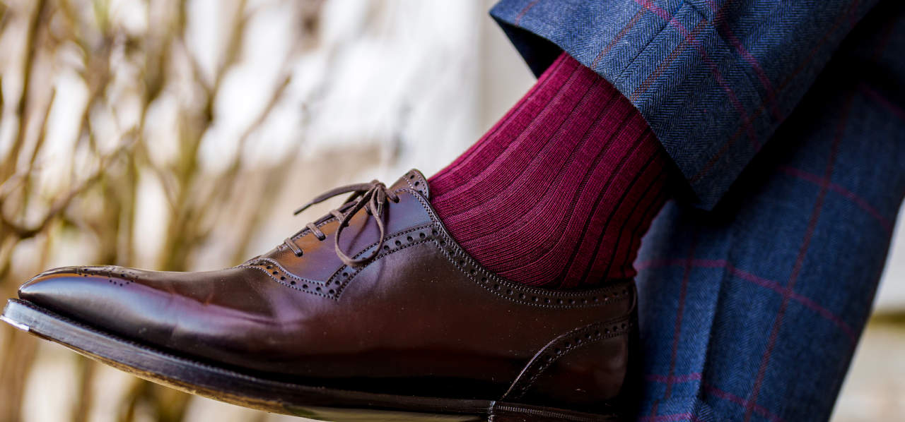man crossing legs wearing burgundy merino wool dress socks