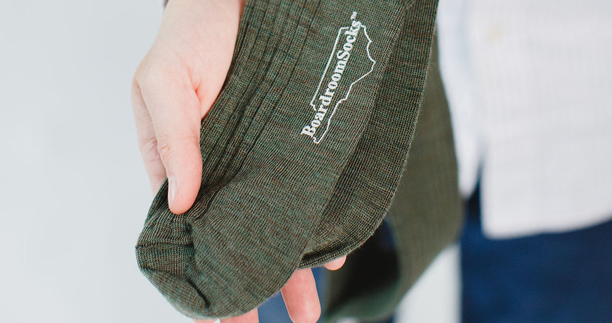 man holding pair of olive green wool dress socks