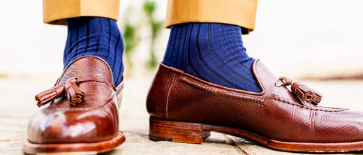 dark brown tassel loafers with navy cotton dress socks and tan trousers