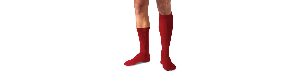 man wearing one pair of red over the calf socks and one pair of red mid calf socks