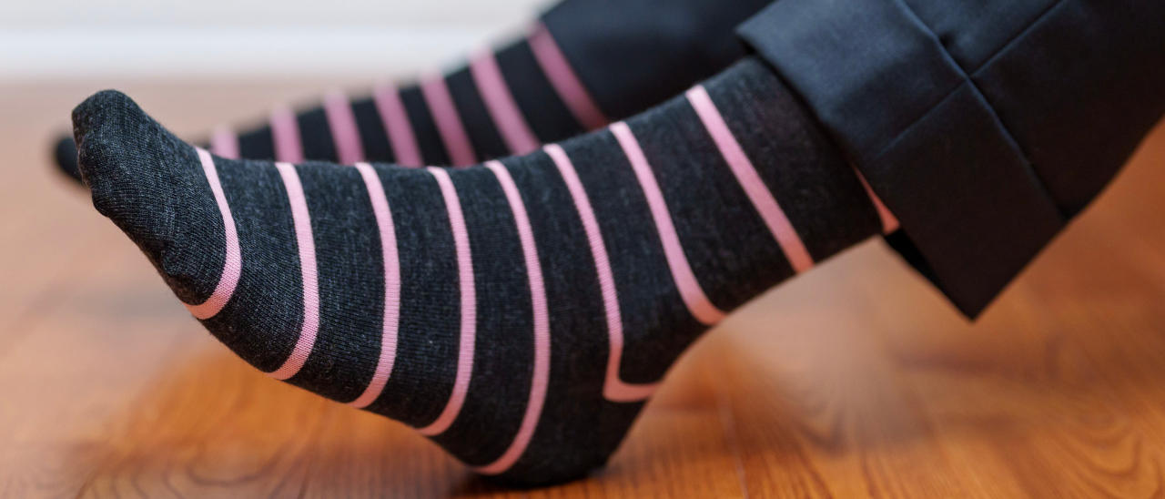 man wearing pink and grey striped patterned dress socks