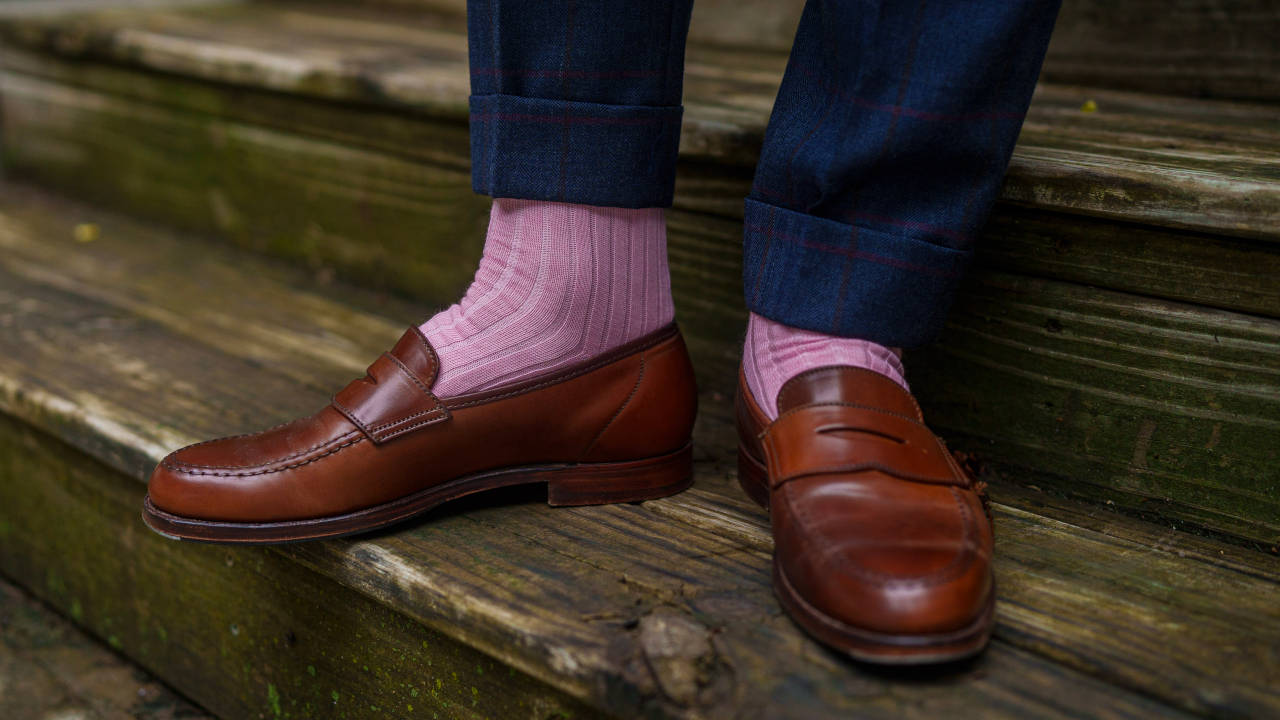 stylish man wearing pink dress socks with plaid suit and brown penny loafers