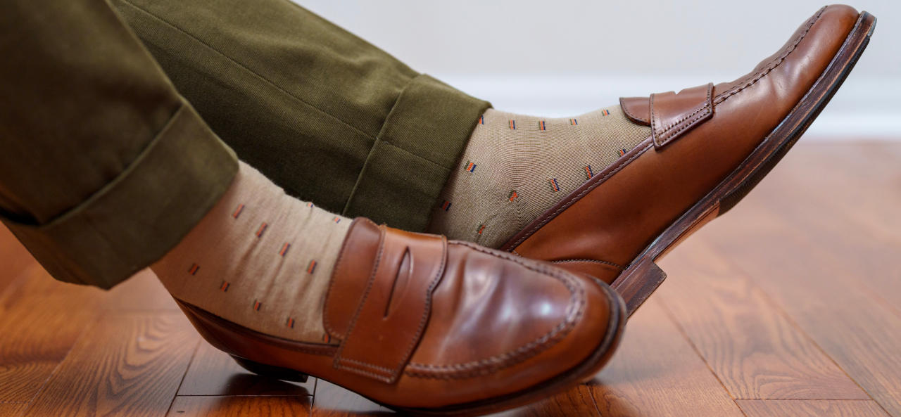 tan patterned dress socks with green suit trousers and brown penny loafers