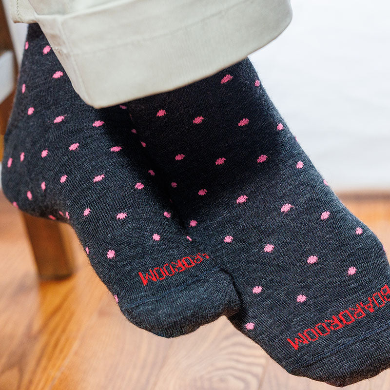 man wearing charcoal grey dress socks decorated with pink dots paired with khaki slacks
