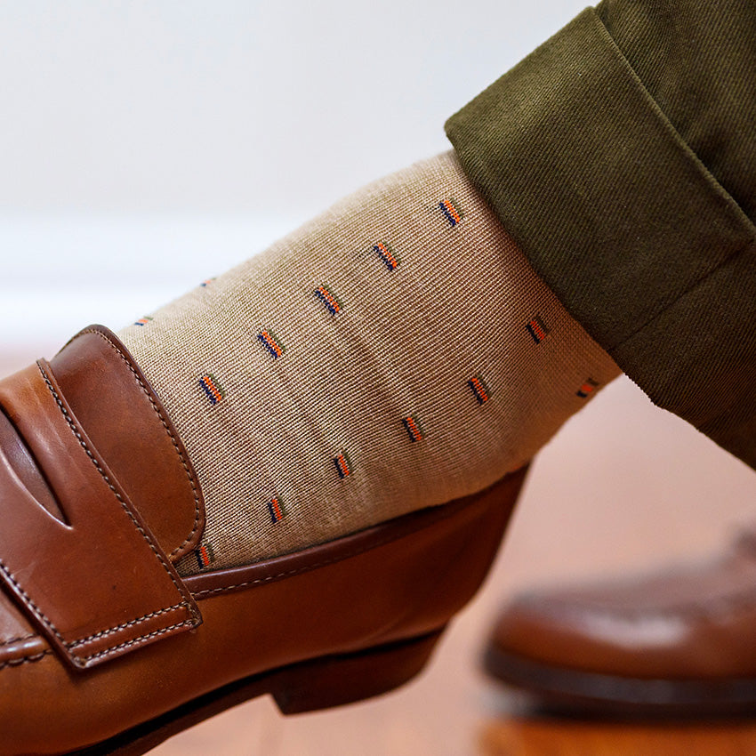 khaki patterned merino wool dress socks for men paired with olive slacks and brown penny loafers