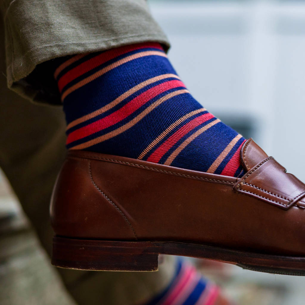 navy dress socks with colorful orange and red horizontal stripes being worn with khaki chinos and brown penny loafers